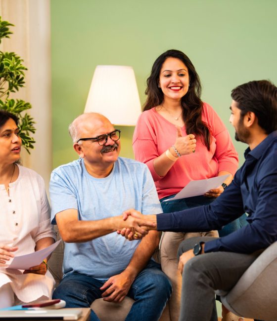 Senior Indian couple with daughter closing deal and shaking hands with male advisor in formal wear after successful presentation. concept of consultation, agreement, and financial planning