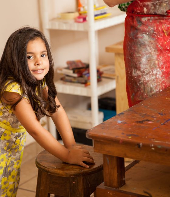Cute little hyperactive girl standing up and moving around during art class